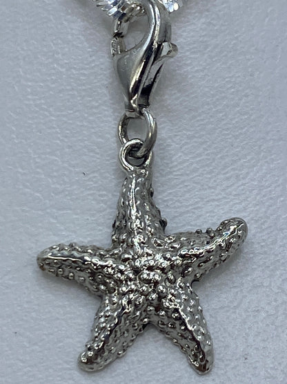 Dije de estrella de 3 cm de largo sobre una regla de medición