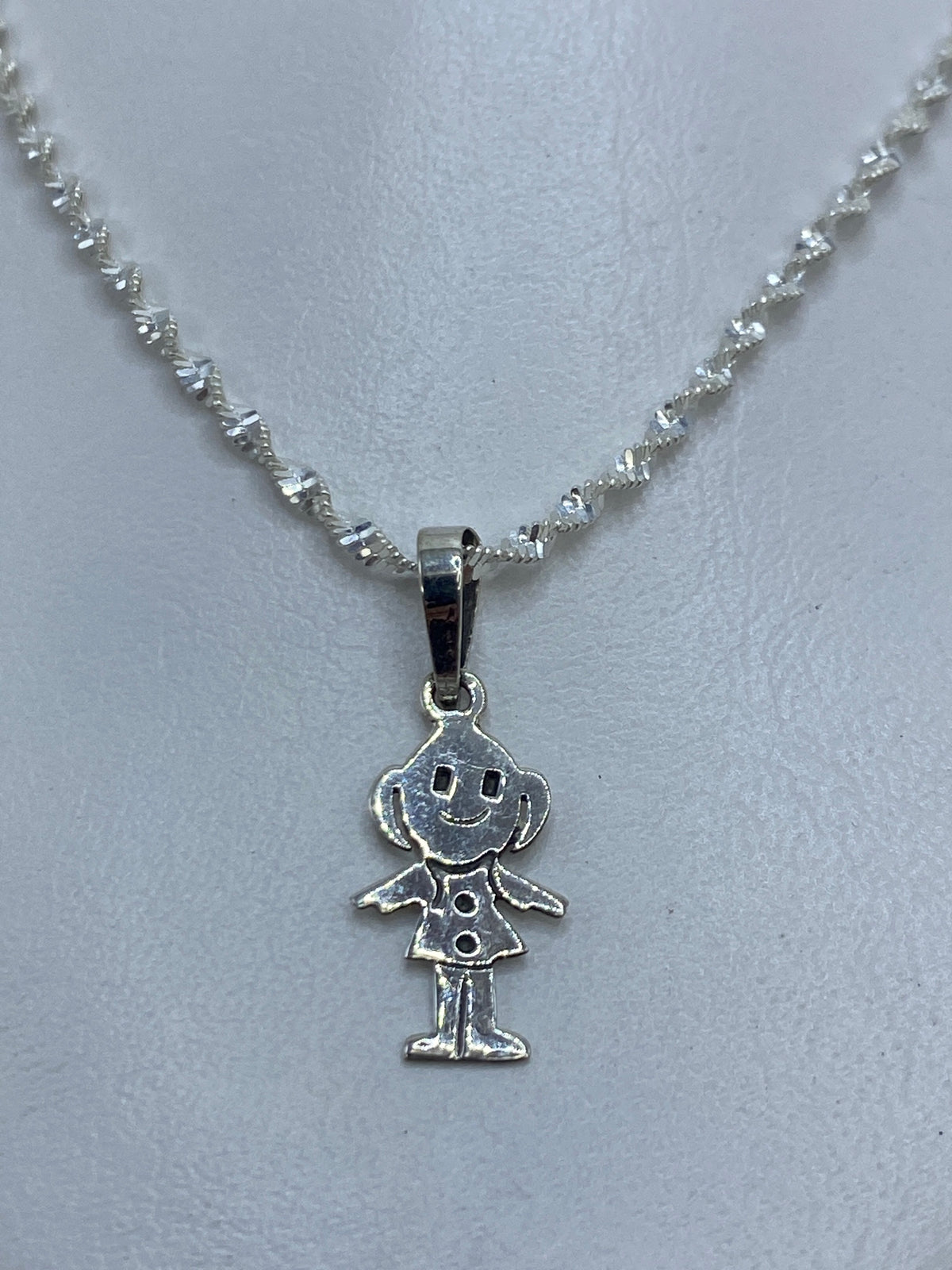 Detalle frontal de la cara sonriente grabada en el dije de plata