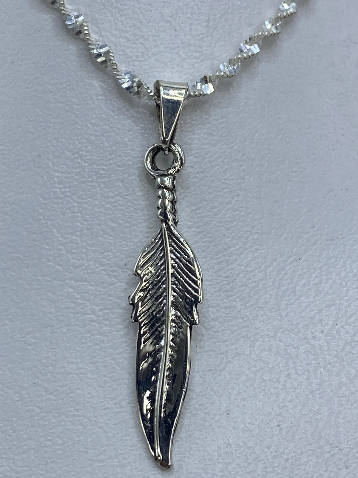 Dije de pluma en plata .925 tallado a mano, mostrado en cadena de eslabones espiral