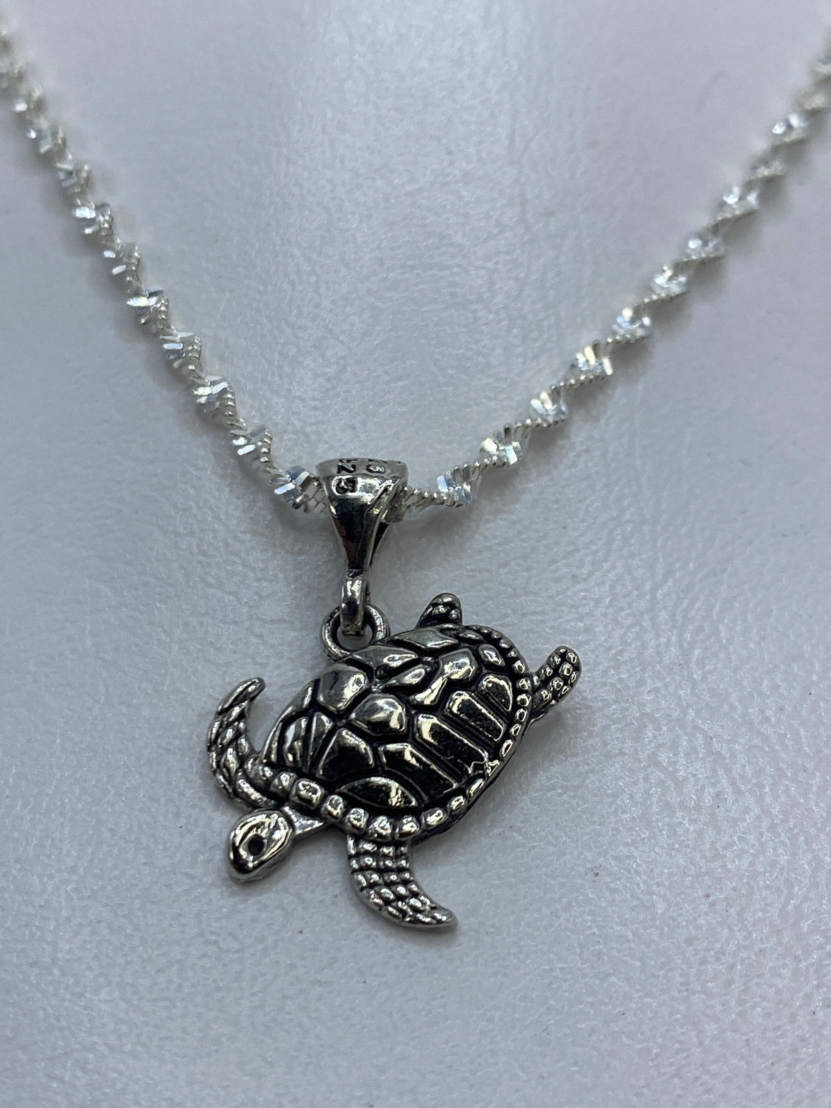 Vista frontal del dije tortuga en plata .925, mostrando el trabajo de repujado artesanal