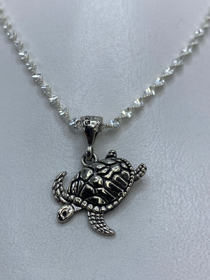 Vista frontal del dije tortuga en plata .925, mostrando el trabajo de repujado artesanal