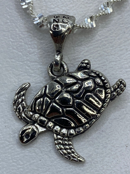 Dije tortuga sobre regla centimétrica, midiendo 2 cm de largo, sin cadena