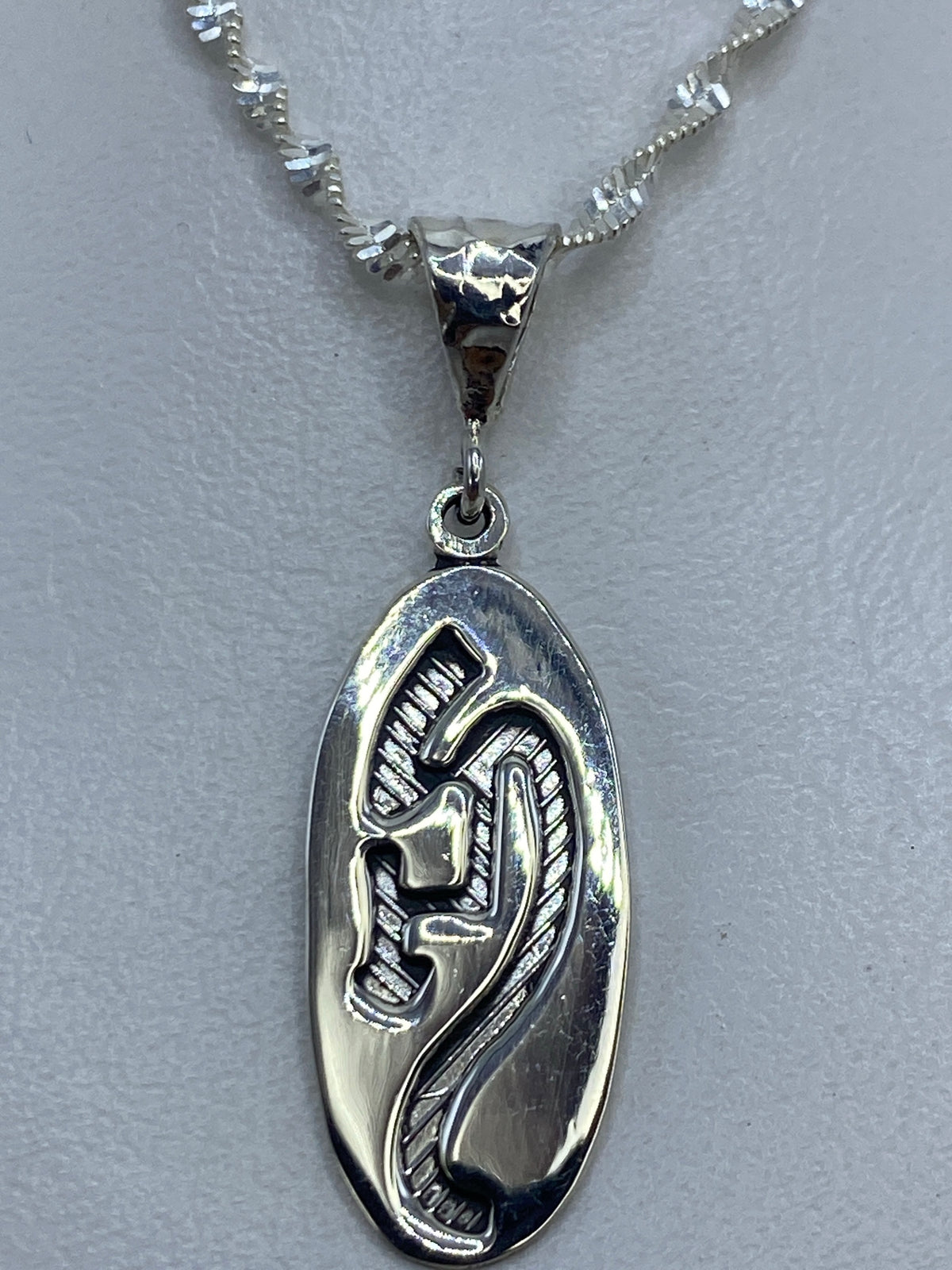 Dije de plata .925 con diseño prehispánico en relieve sobre fondo gris claro