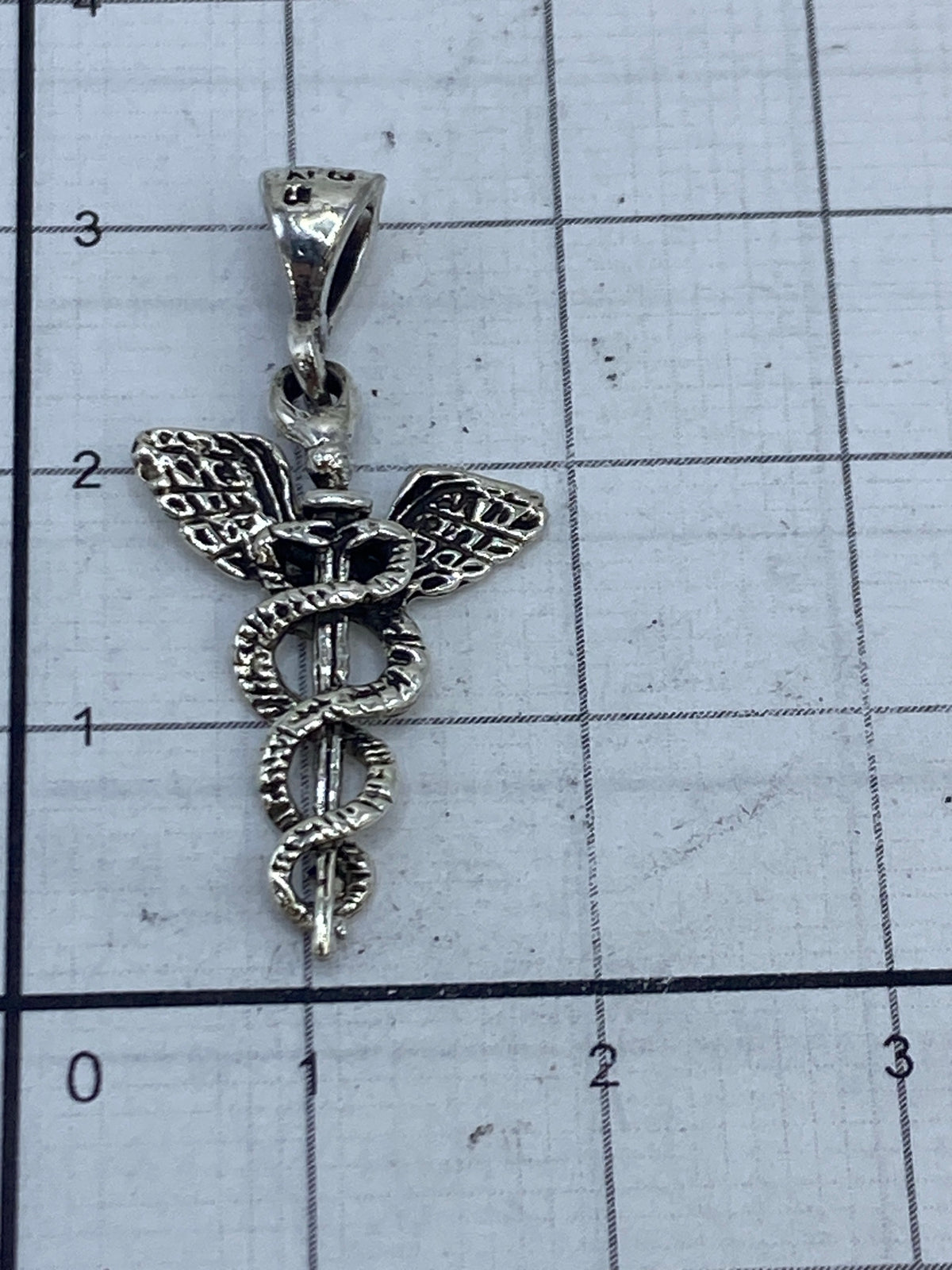 Caduceo de plata en la mano, tamaño comparativo discreto y portátil