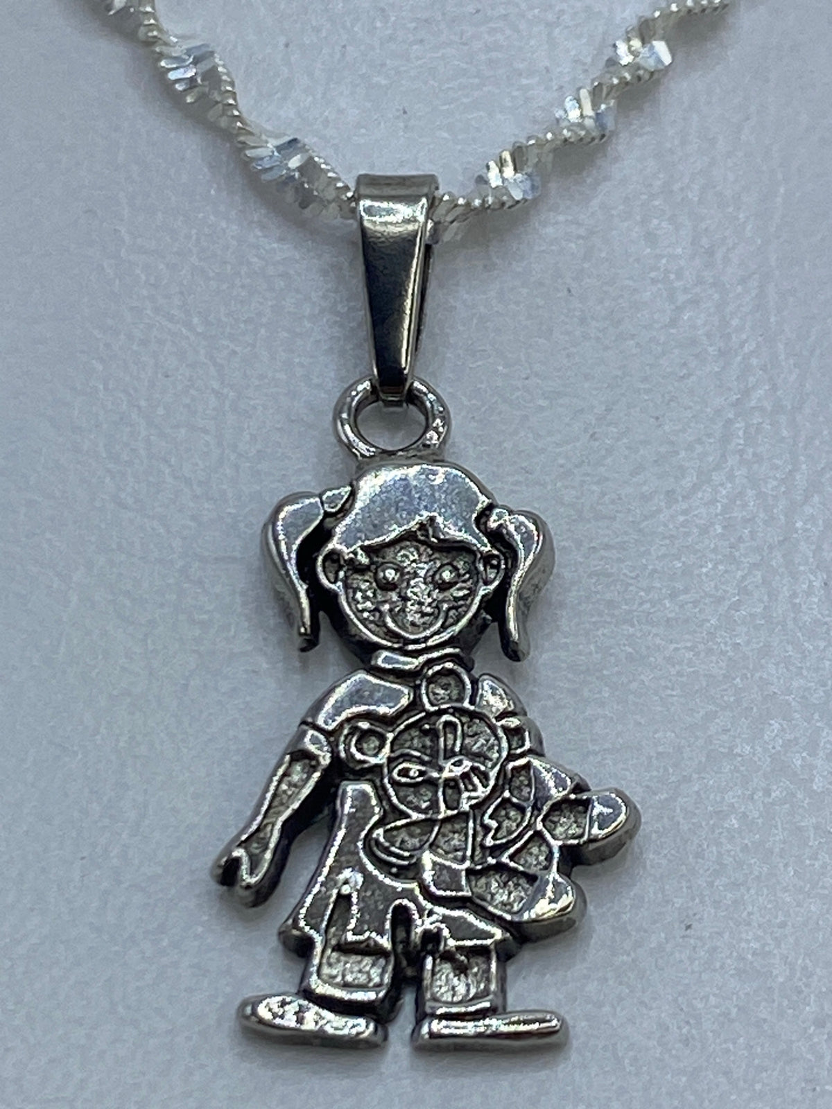 Dije de plata repujado en forma de muñequita con vestido detallado, 3 cm de largo