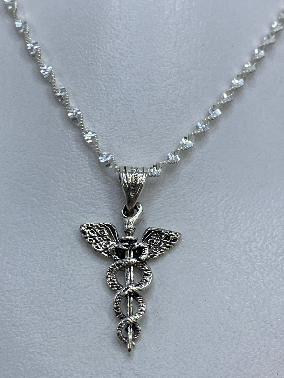 Vista frontal detallada del caduceo con alas y serpientes en plata 925