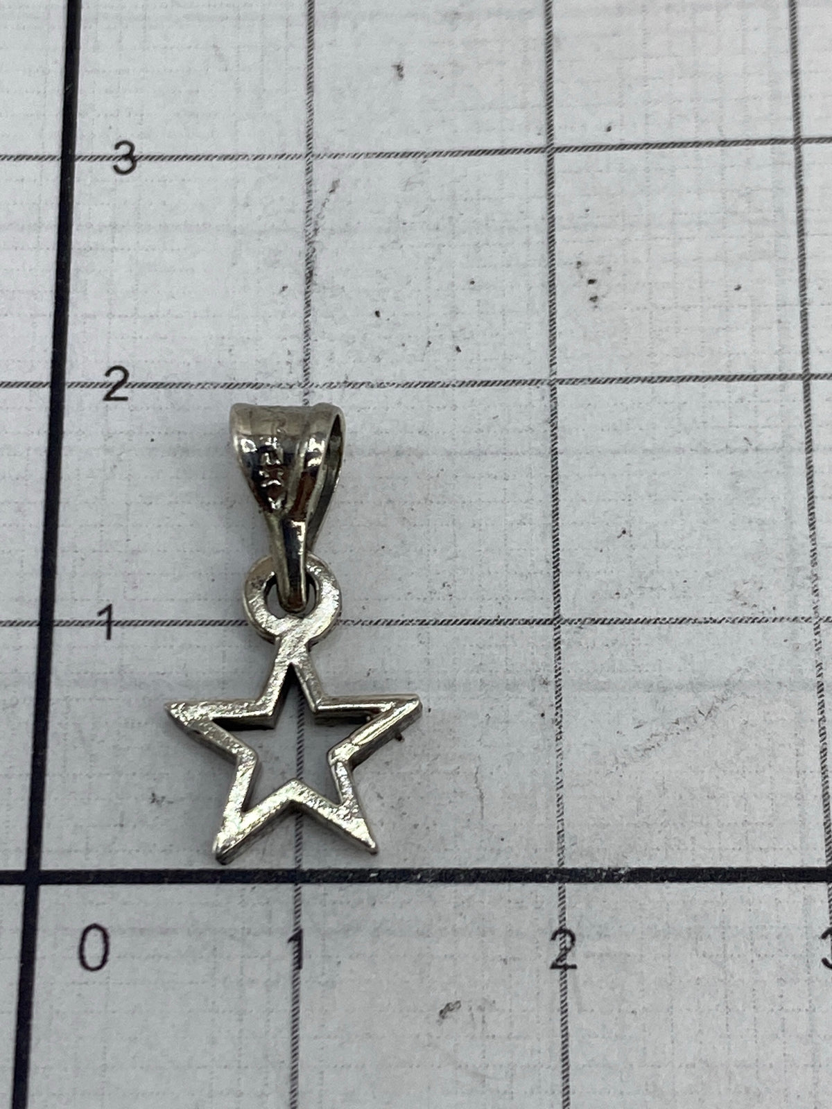 Dije de estrella en una báscula mostrando 0.7 gramos