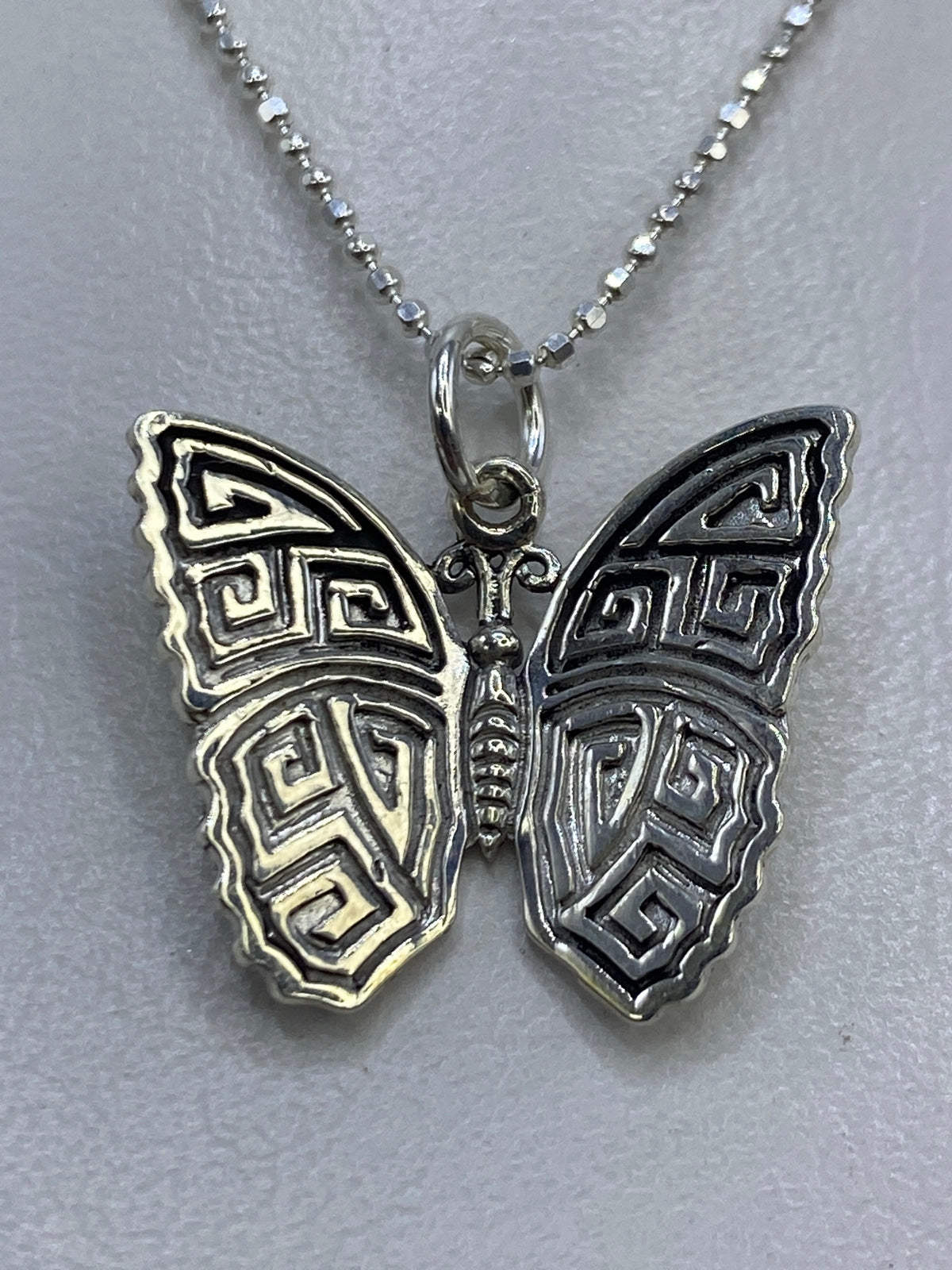 Dije de plata 925 en relieve repujado con motivos prehispánicos, 2 cm de largo