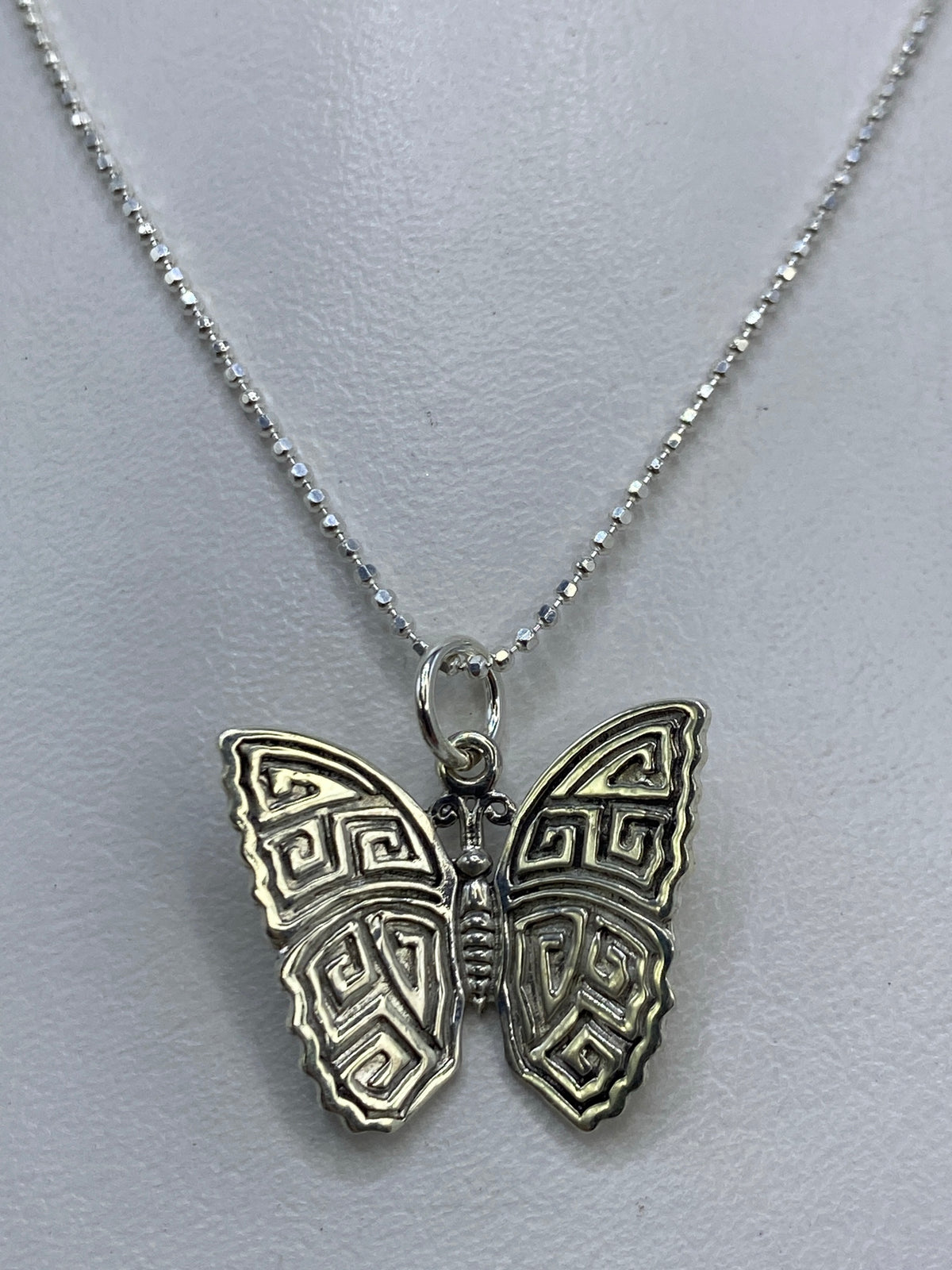 Detalle del patrón prehispánico en el dije de mariposa con repujado a mano