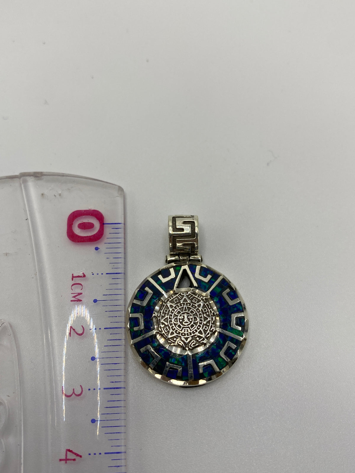 Reverso del dije mostrando el acabado pulido y el Quinto .950 grabado