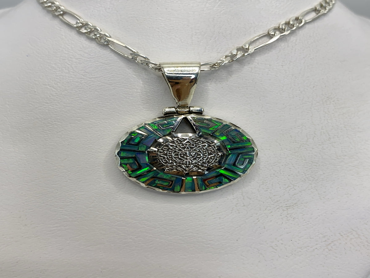 Dije de plata .950 con Ópalo de Fuego azul cielo y motivos prehispánicos labrados, colgando de una cadena figaro