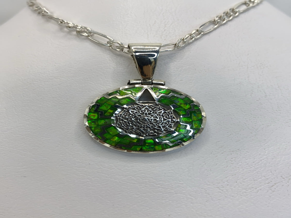 Dije de plata .950 con Ópalo de Fuego verde y diseño prehispánico, colgando de una cadena plateada