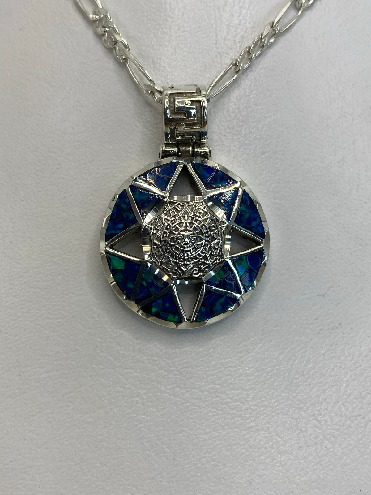 Dije de plata .950 con Calendario Azteca y ópalo de fuego azul engastado, visto de frente