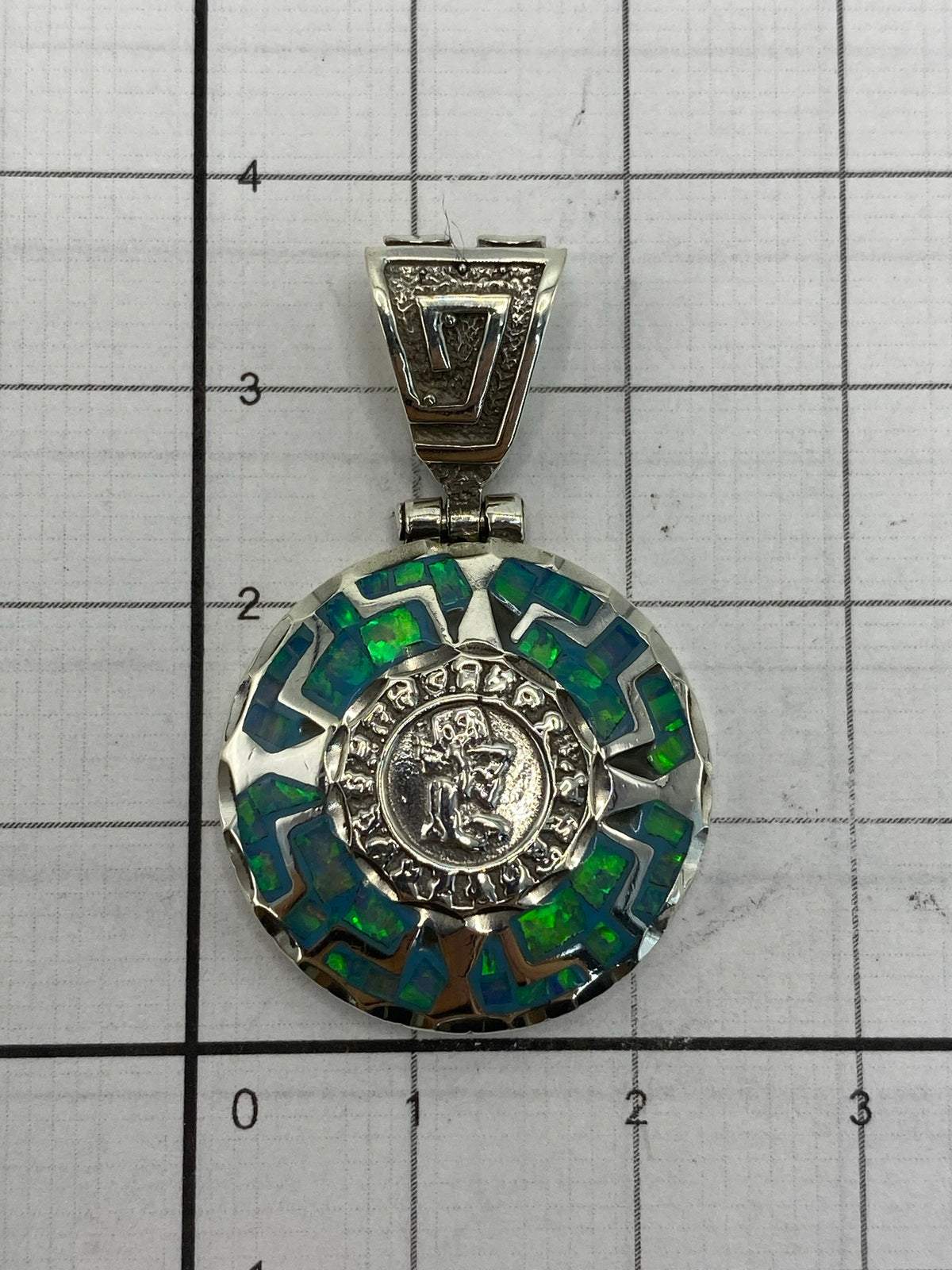 Dije de 3.5 × 2.2 cm sobre escala de medidas — tamaño elegante puesto