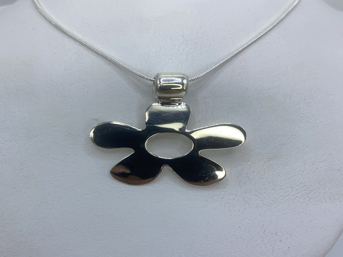 Dije de plata calado de cinco pétalos, 3 cm, colgando de cadena de plata sobre fondo blanco