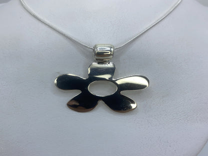 Dije de plata calado de cinco pétalos, 3 cm, colgando de cadena de plata sobre fondo blanco