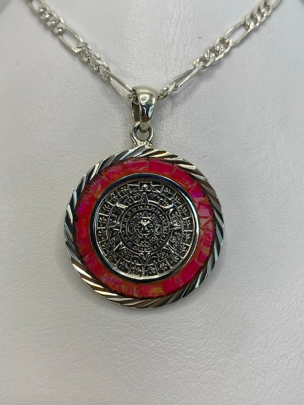Detalle frontal del Calendario Azteca y el engaste manual del ópalo de fuego en tonos rosa y dorado