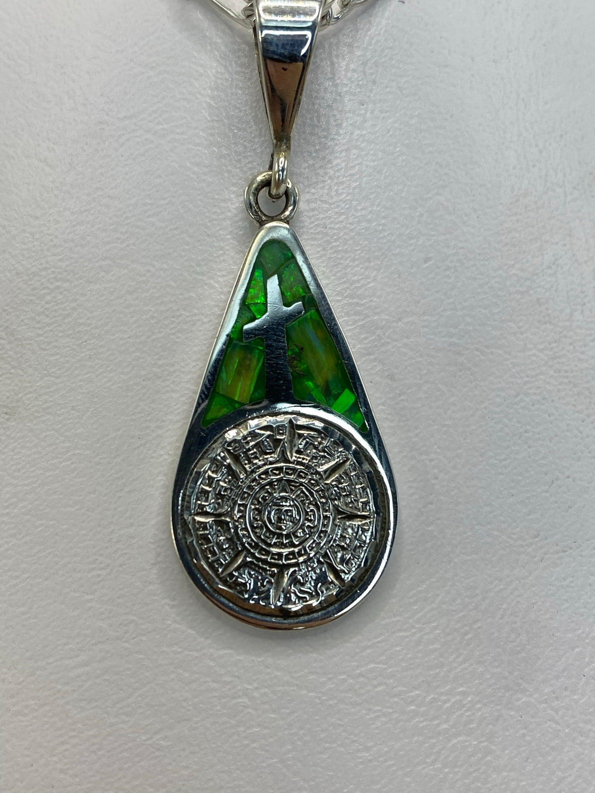 Dije en forma de gota de plata .950 con Calendario Azteca en relieve y ópalo de fuego verde, visto de frente