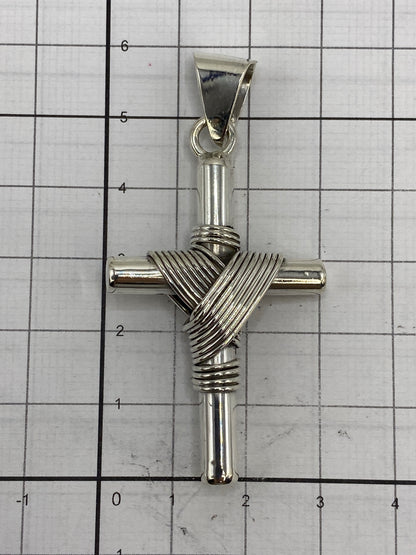 Dije cruz de plata sobre fondo neutro con escala en centímetros
