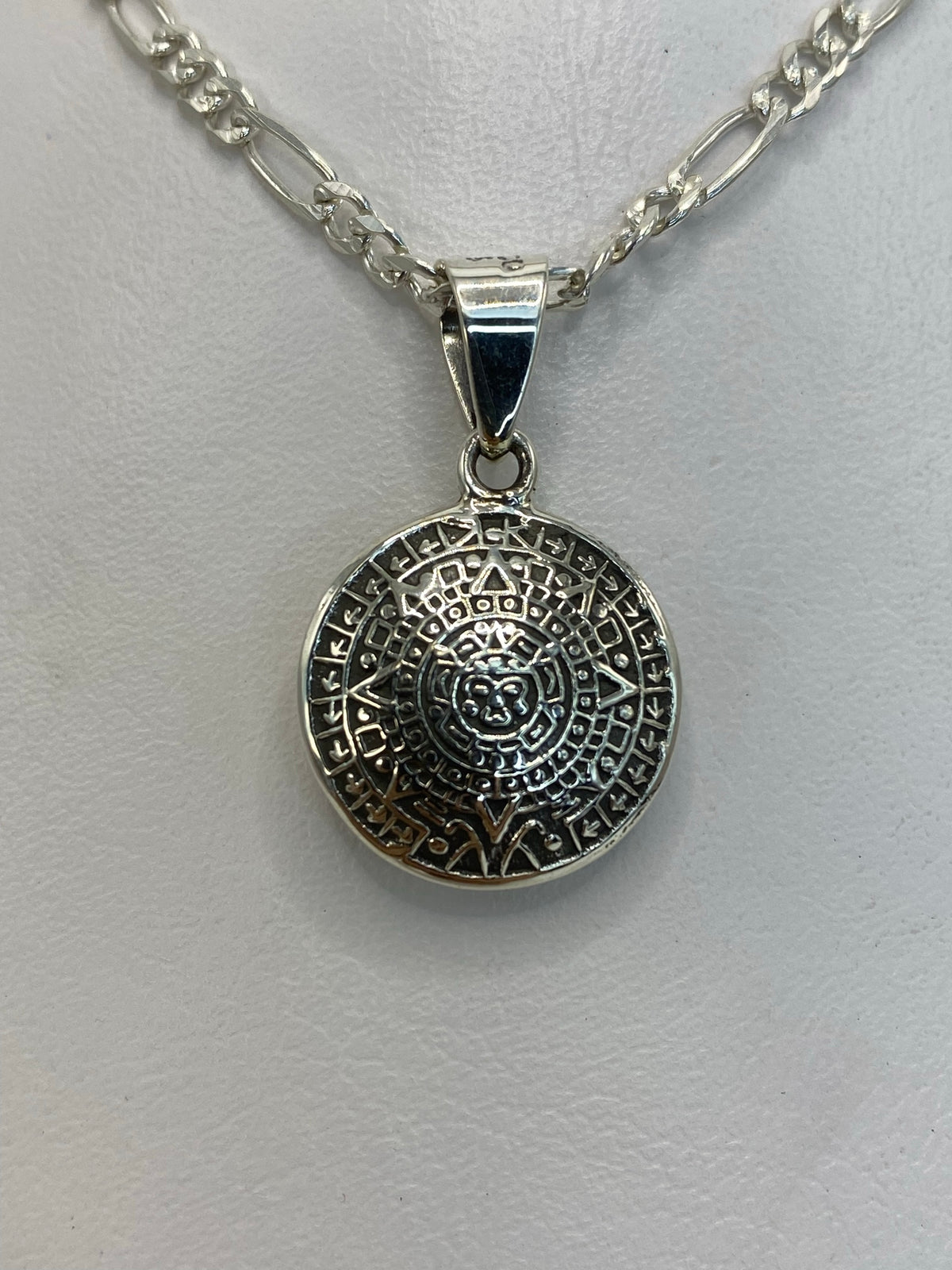 Dije de plata con diseño del Calendario Azteca, vista frontal del círculo con glifos prehispánicos