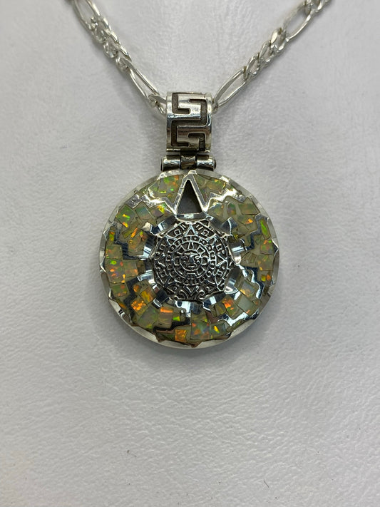 Dije de plata .950 con calendario azteca y ópalo de fuego blanco, colgado de cadena plateada