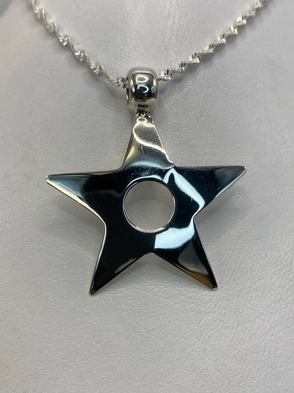 Dije de plata estrella de cinco puntas en relieve sobre fondo blanco