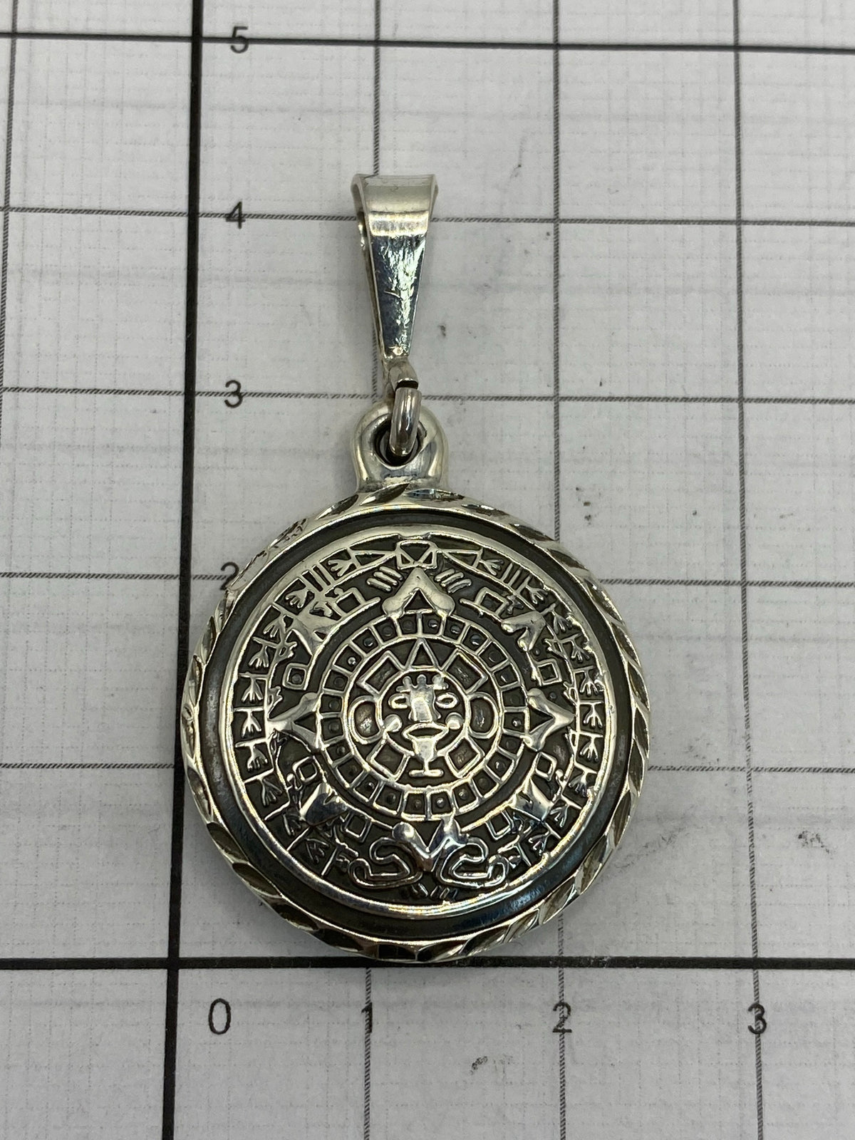 Reverso del dije de plata fundida con acabado pulido, mostrando el borde con cuerda