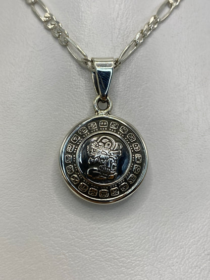 Dije de plata con calendario azteca prehispánico, 2.8 cm de largo, colgando sobre fondo blanco
