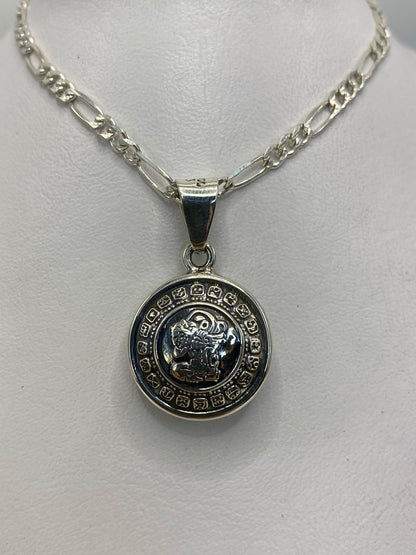 Detalle frontal del dije redondo con glifos grabados y figura central azteca en plata