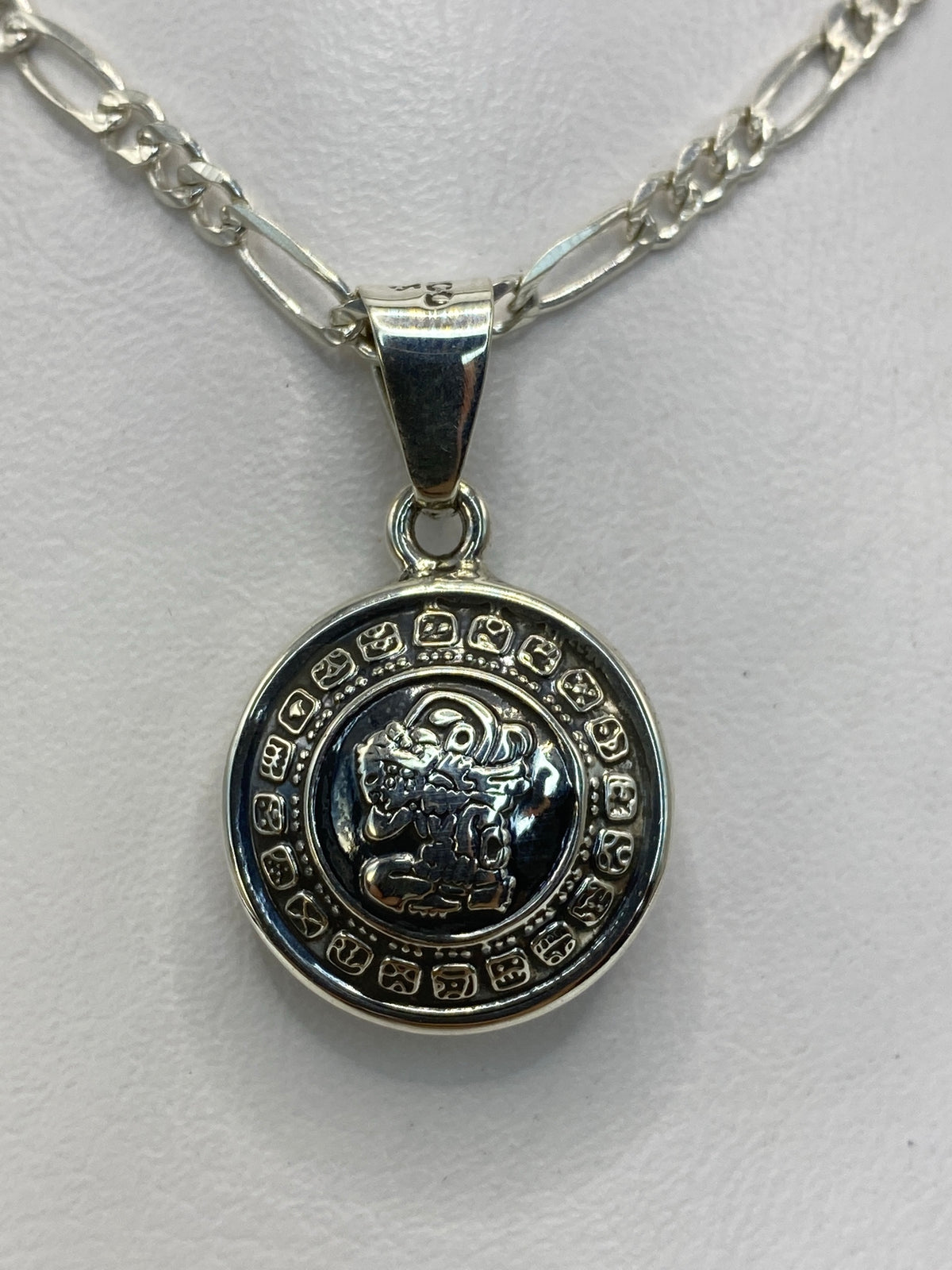Dije de plata sobre regla, mostrando las dimensiones de 3 × 2 cm