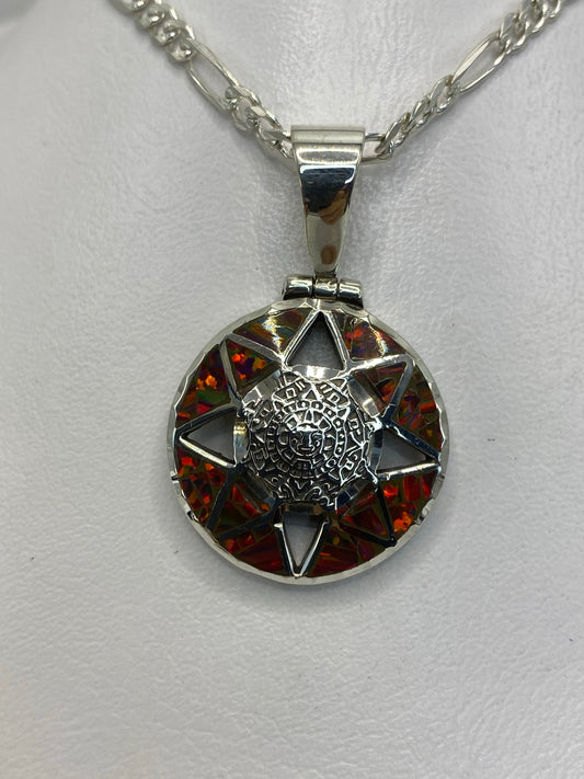 Dije de plata 950 con ópalo de fuego multicolor y diseño prehispánico labrado, suspendido en cadena plateada