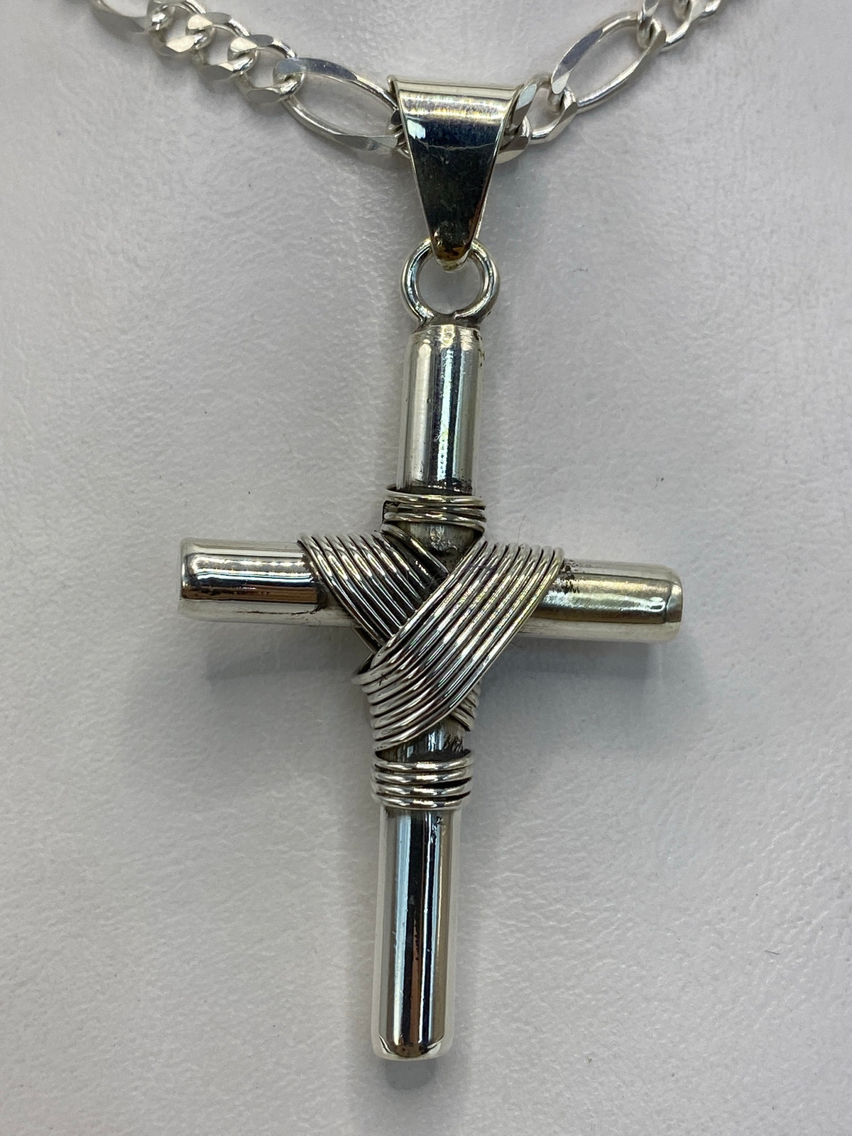 Dije cruz de plata sobre fondo blanco mostrando el Quinto 925