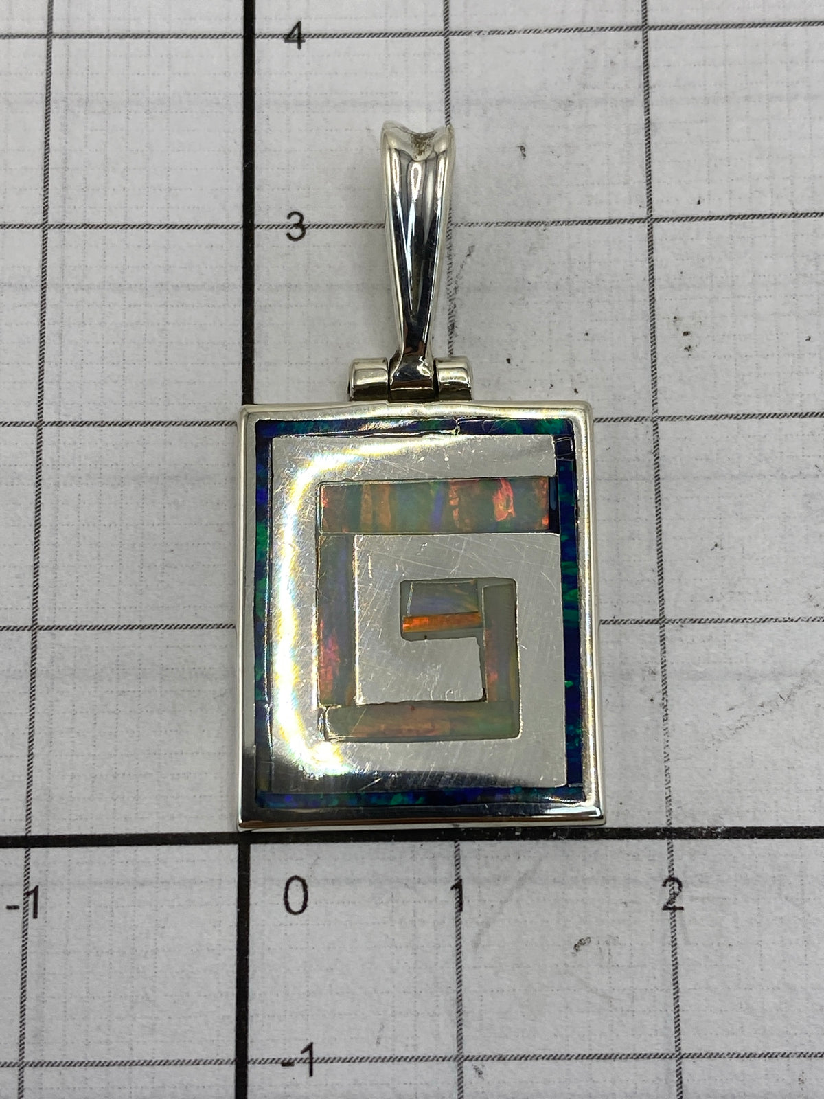 Reverso del dije con el Quinto 950 gravado, sobre fondo blanco