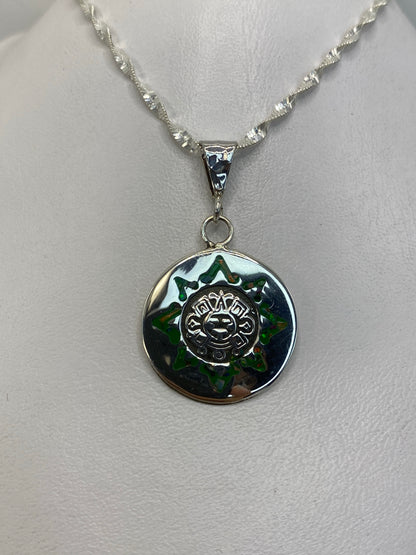 Detalle frontal del sol mexica con piedra ópalo de fuego en tonos verdes y dorados