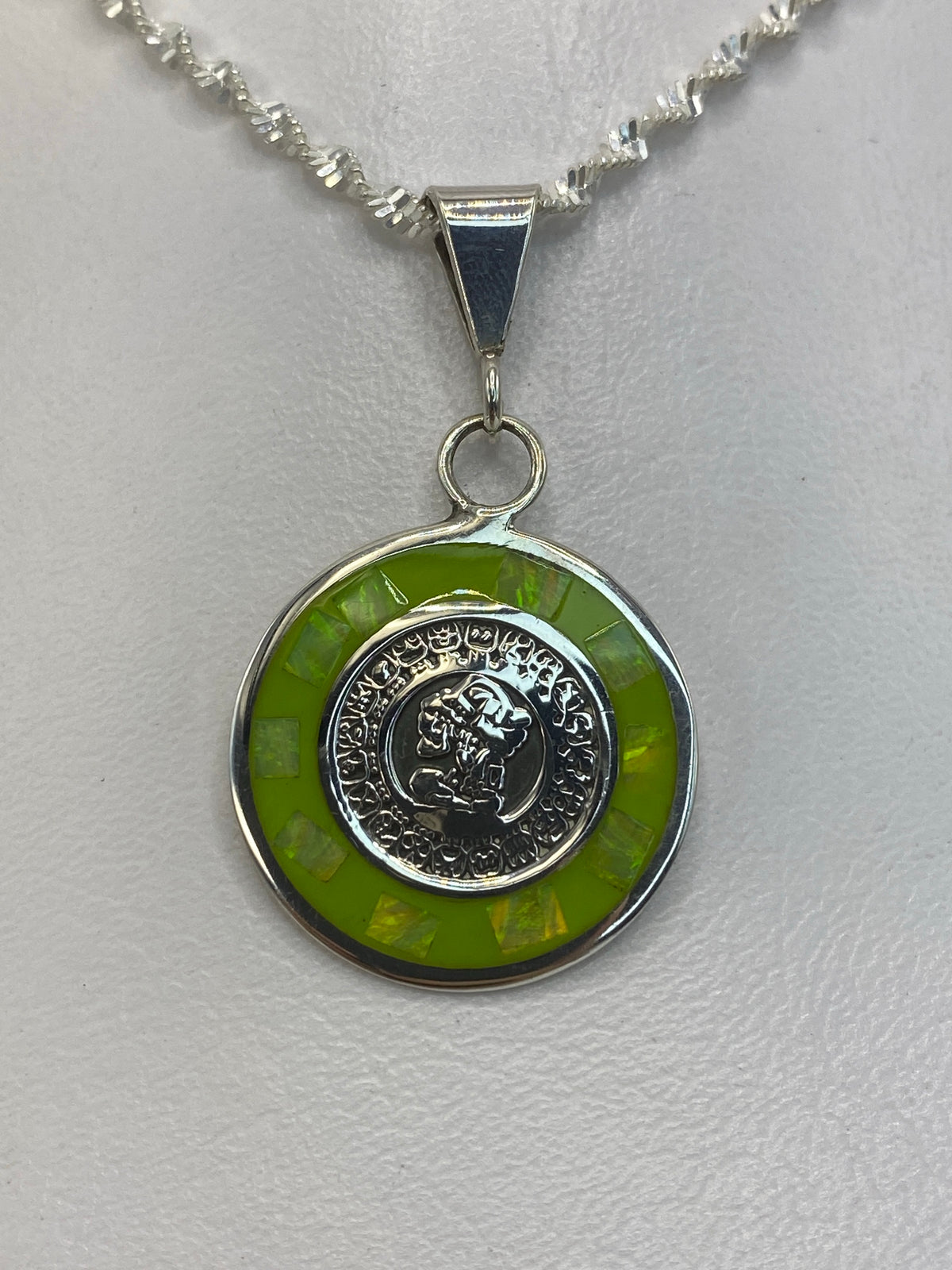 Vista lateral del dije de 3.5 cm con moneda tallada en plata 925, mostrando el engaste de la piedra