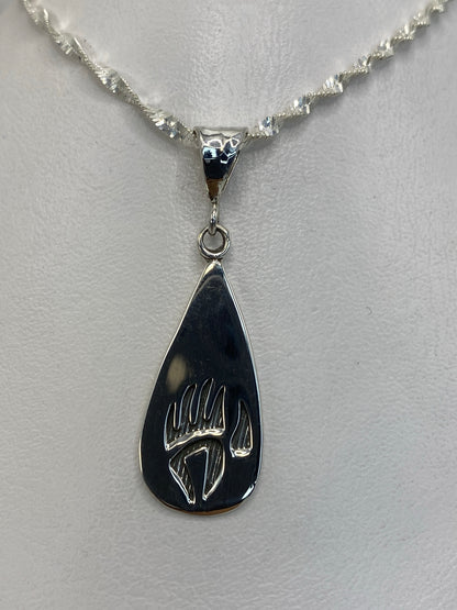 Dije de plata garra de oso colgante sobre fondo blanco, vista frontal del diseño grabado