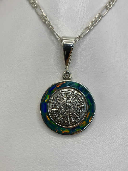 Dije Calendario Azteca de plata 950 con Ópalo de Fuego azul, colgante en cadena de eslabones sobre fondo blanco