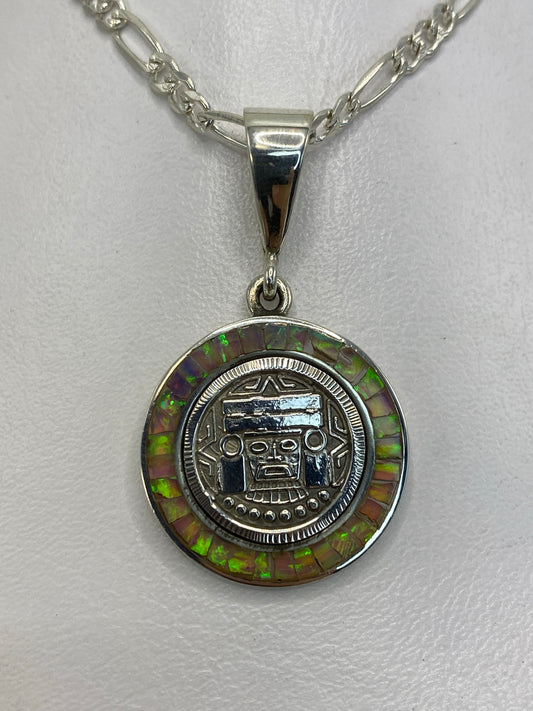 Dije prehispánico de plata 950 con rostro de deidad mexica y ópalo de fuego multicolor en marco de concha