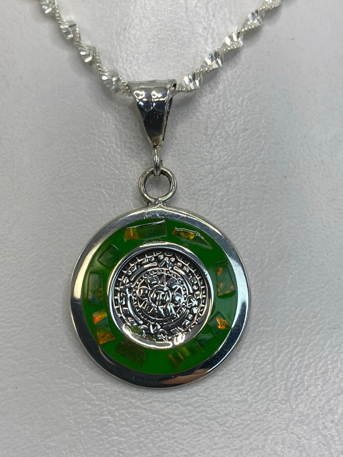 Detalle del ópalo de fuego verde brillando en el dije de plata