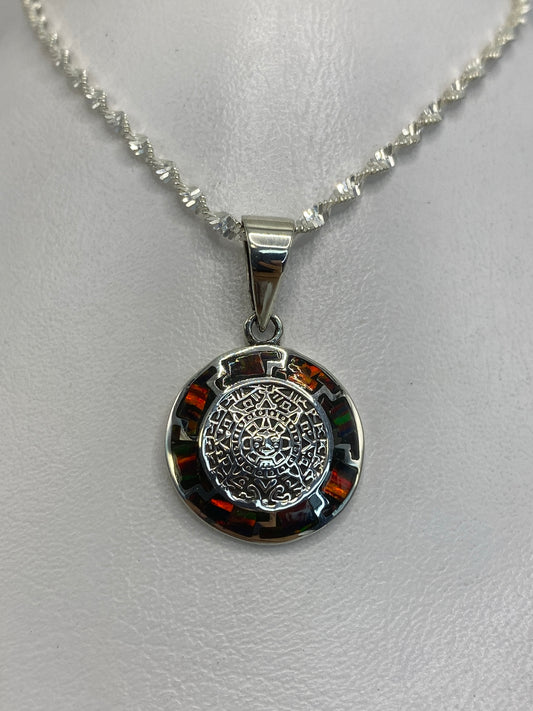 Dije de plata 950 con mandala azteca en relieve y ópalo de fuego naranja colgando de cadena plateada