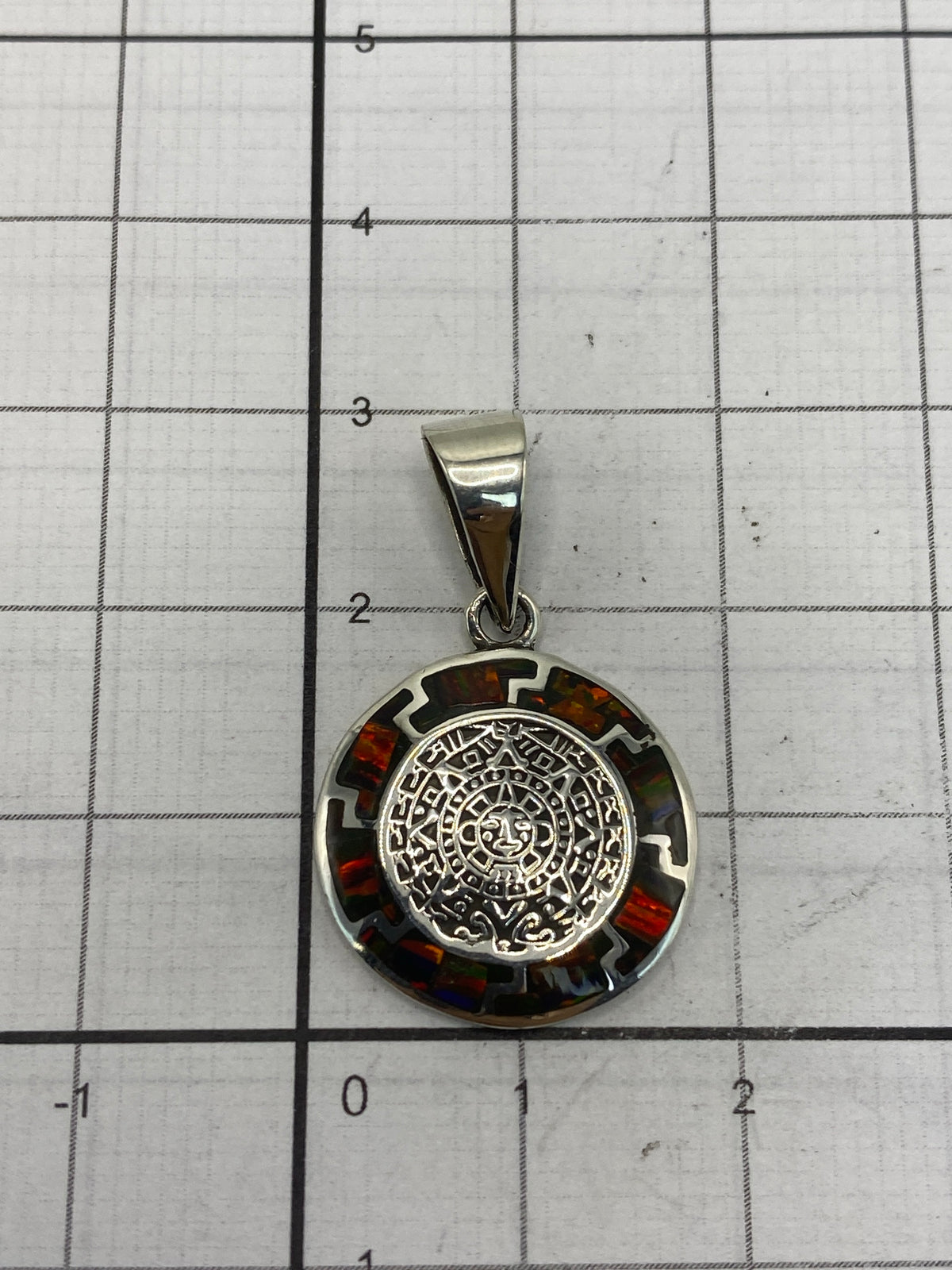 Dije de mandala azteca de 3 cm sobre regla — tamaño discreto y visible
