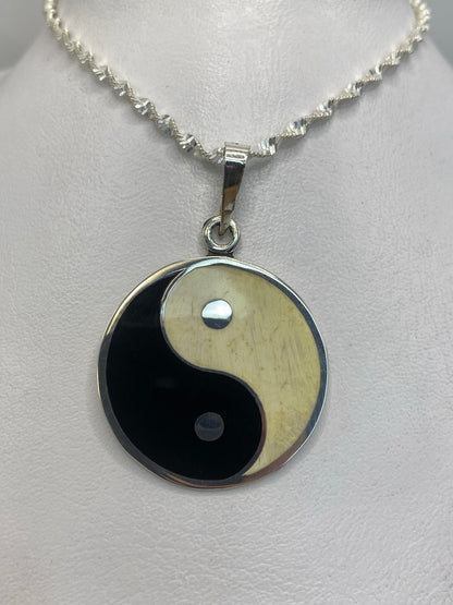 Detalle frontal del dije yin-yang mostrando el acabado pulido de espejo en plata