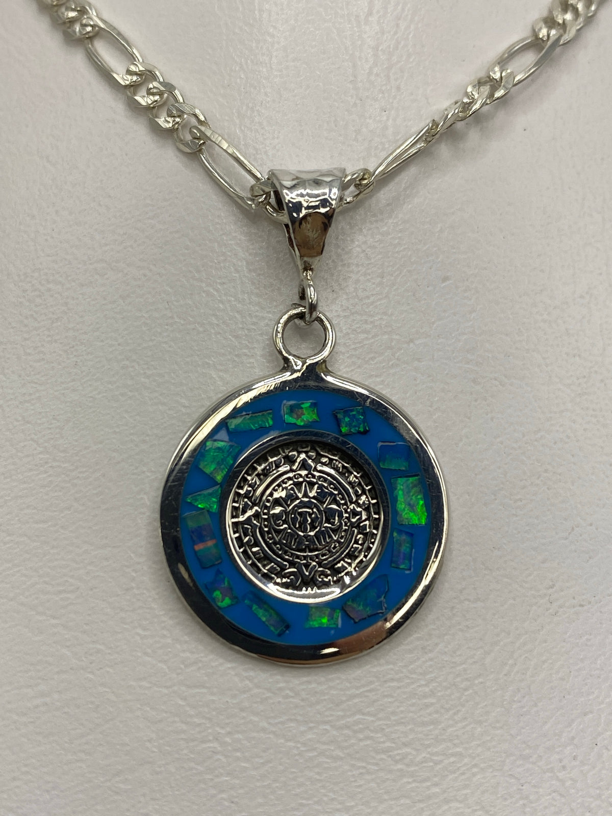 Dije de plata con Calendario Azteca y ópalo de fuego azul colgando de cadena de plata figaro