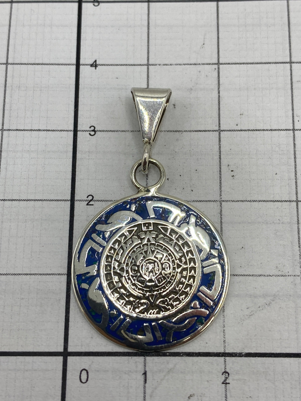 Dije Calendario Azteca sobre escala de gramos mostrando su tamaño real de 3.5 cm