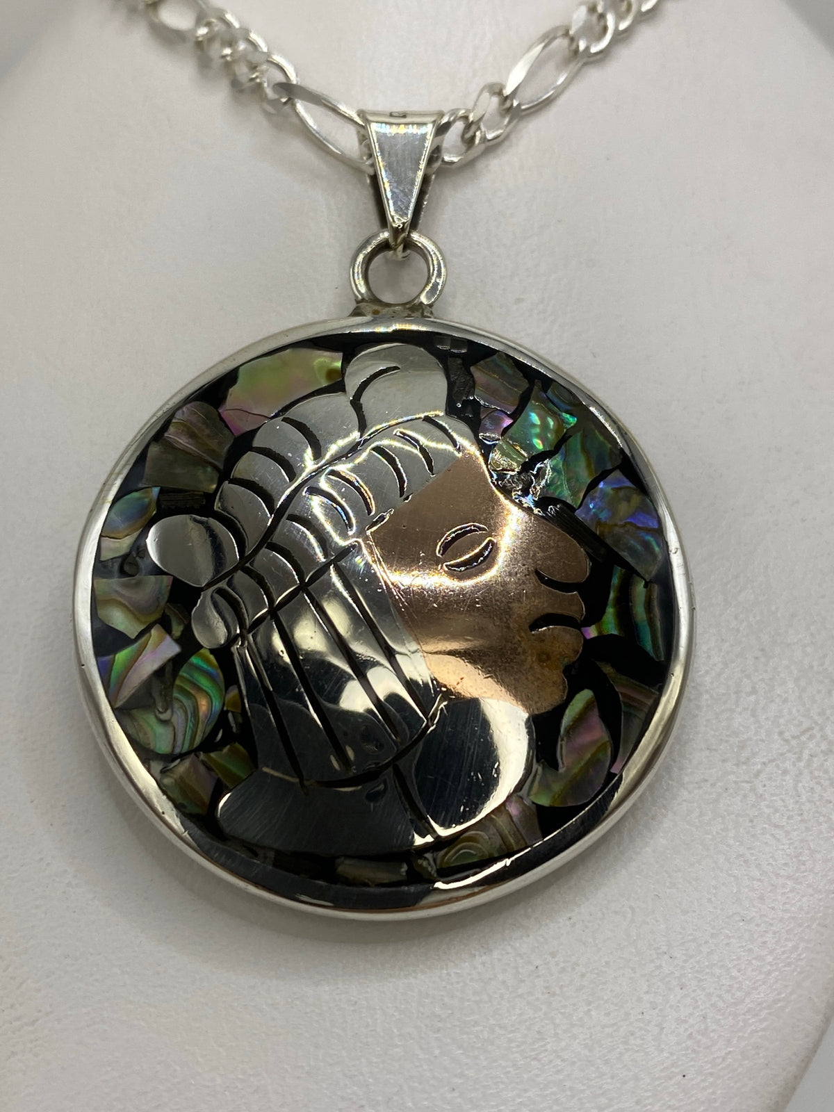Dije de plata 925 prehispánico con rostro de guerrero de perfil, tocado de plumas grabadas y fondo de nácar iridiscente