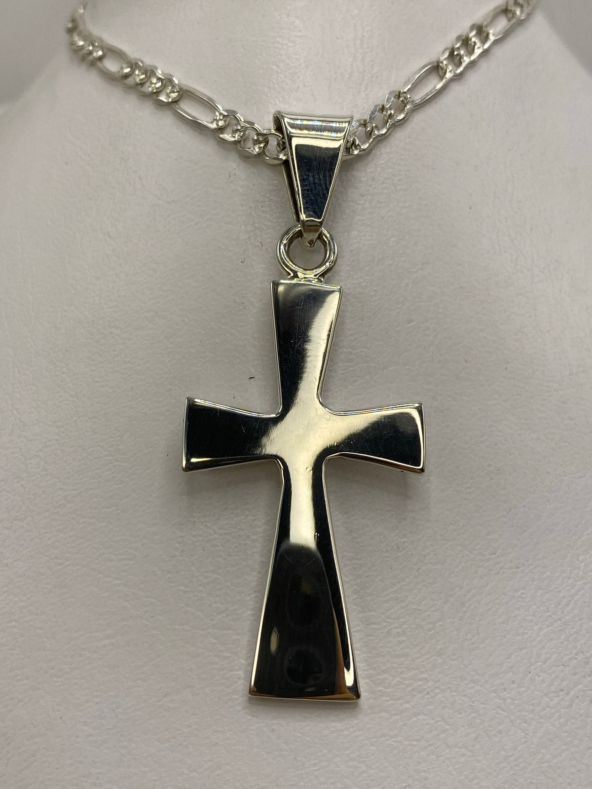 Dije cruz de plata 925 de Taxco con lados biselados, colgando de cadena figaro