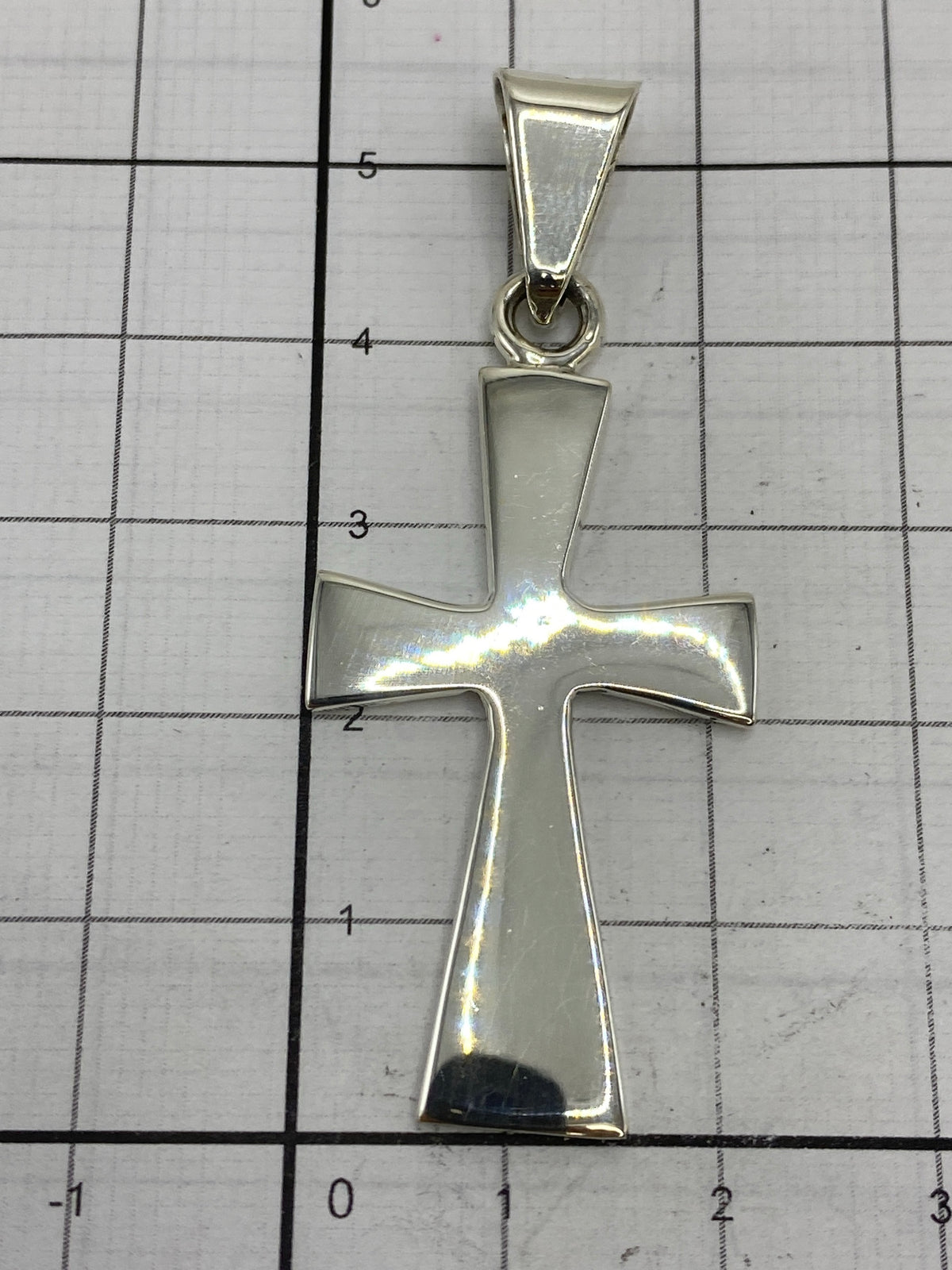 Dije cruz de plata en la palma de la mano, proporción real de tamaño