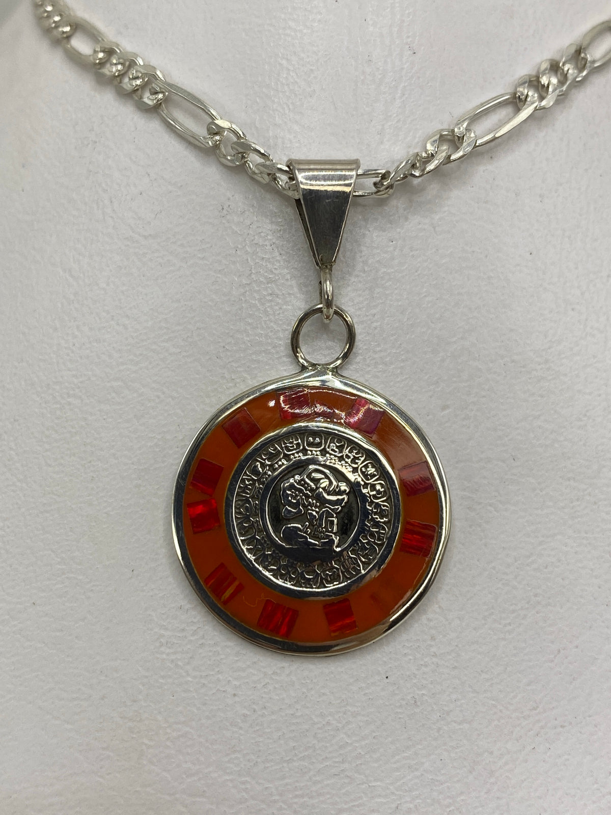 Dije de plata con ópalo de fuego rojo en diseño prehispánico, colgado de una cadena figaro de plata