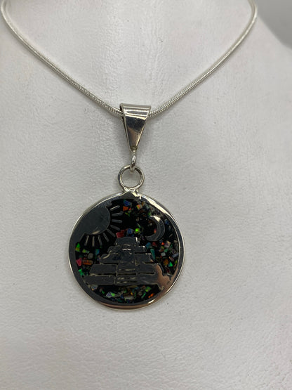 Detalle del dije mostrando la pirámide escalonada, símbolos de sol y luna, y los colores del ópal de fuego