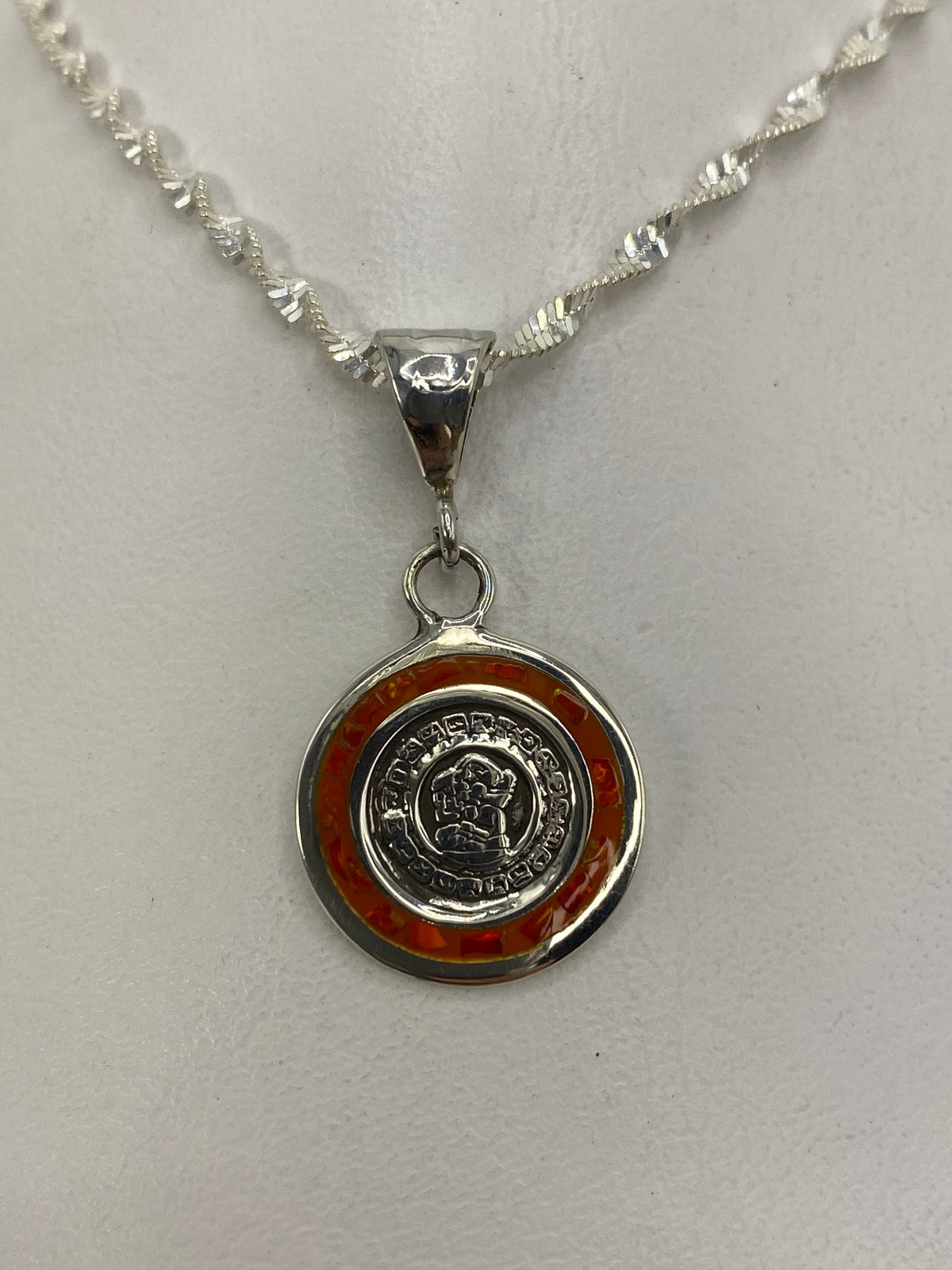 Dije de plata circular con Ópalo de Fuego naranja y motivo prehispánico grabado, colgado de cadena